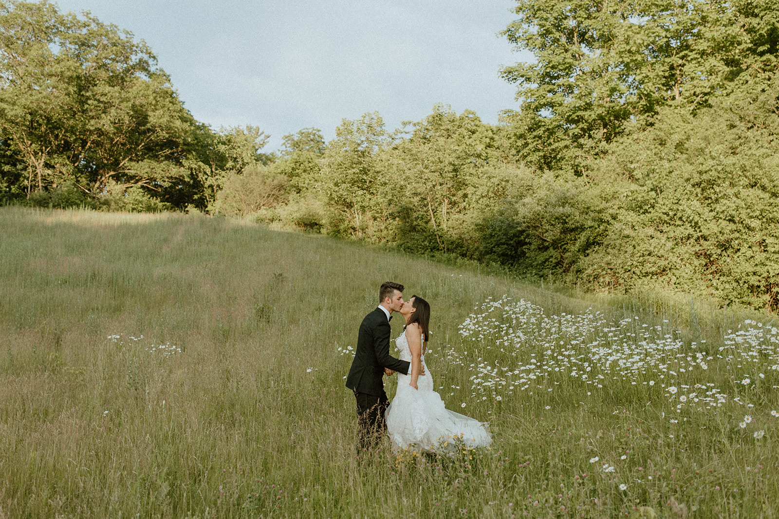 Emma Coss Wedding Photography Portrait of Bride and Groom Kissing in a field